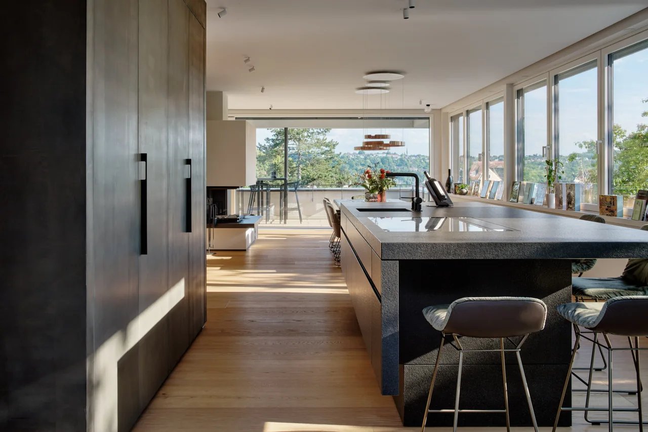Wohnraum mit Holzboden und dunkler Kücheninsel in der Villa Geiselbäche