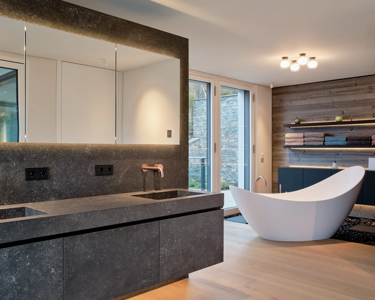 Bad mit Naturstein, Holz und freistehender Wanne in der Villa Geiselbäche